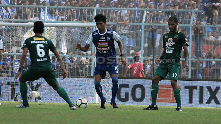 Jayus Hariono mencari celah untuk mengalirkan bola diantara hadangan dua gelandang Persebaya. Copyright: Ian Setiawan/INDOSPORT