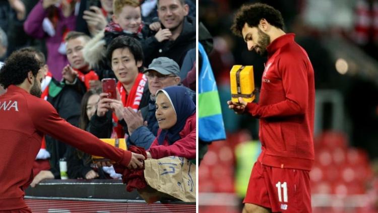Mohamed Salah menerima hadiah dari penggemar saat Liverpool vs Red Star Belgrade. Copyright: Reuters/Empic Sports