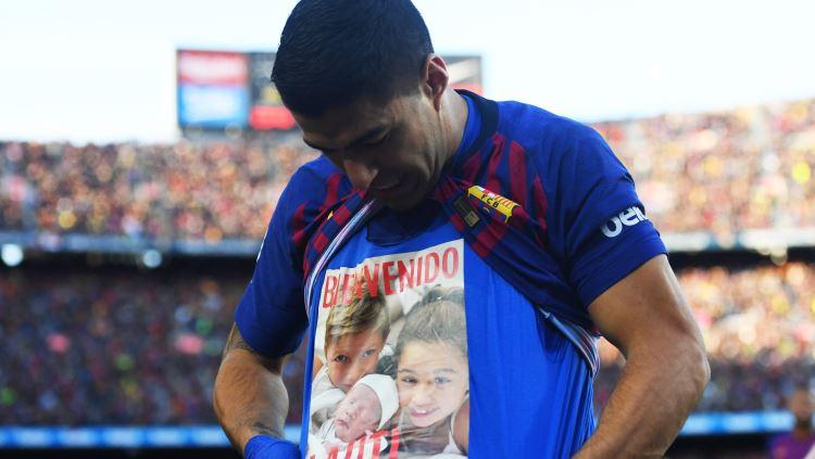 Luis Suarez saat menunjukkan kaos bergambar ketiga anaknya. Copyright: Eurosport