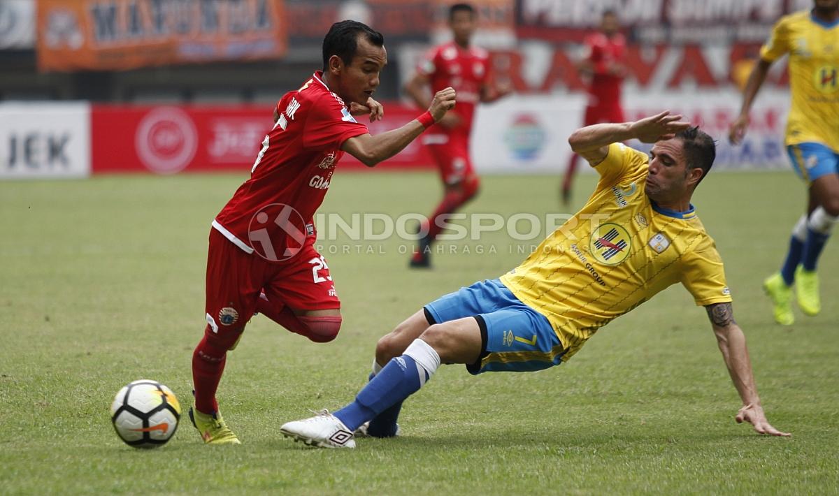 Riko Simanjuntak menghindari jegalan dari pemain Barito Putera.