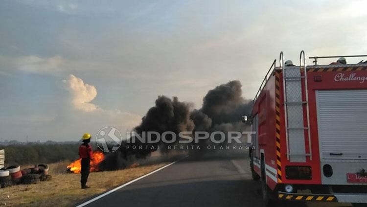 Kericuhan terjadi di luar area stadion gbt. Petugas PMK berusaha memadamkan api dari ban, lokasi terjadi di Sirkuit Gelora Bung Tomo. Copyright: Fitra Herdian/INDOSPORT