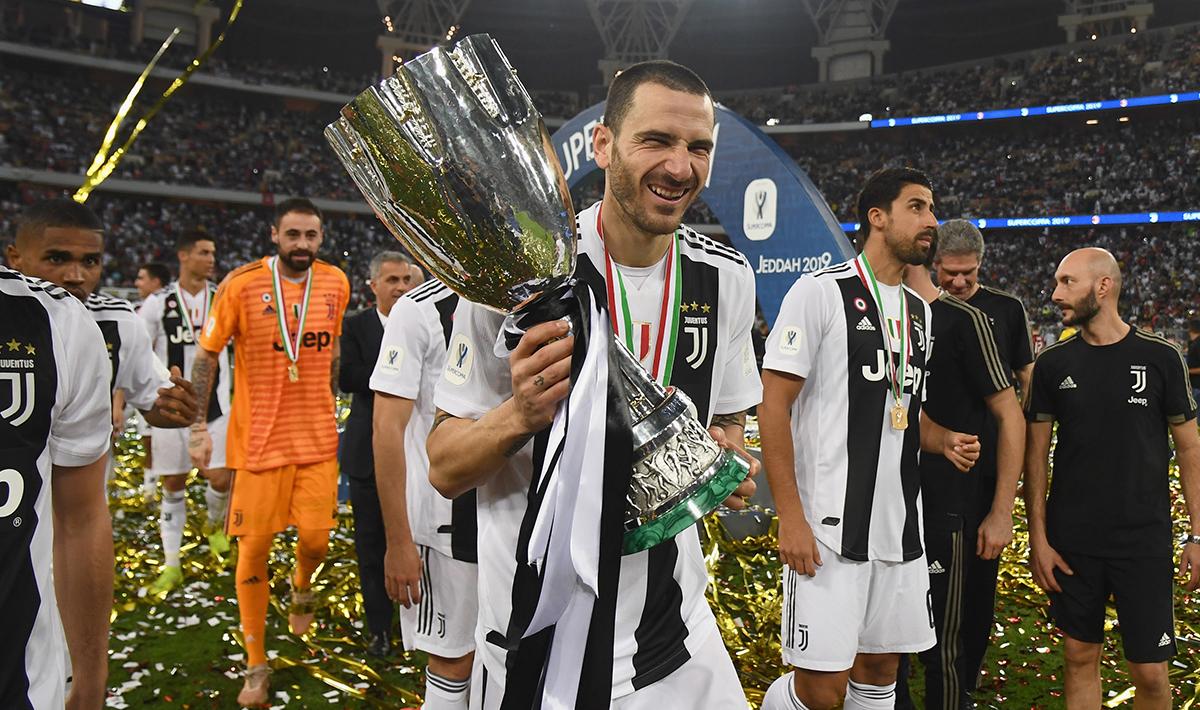 Leonardo Bonucci tengah membawa trofi Supercoppa Italiana sambil tersenyum dengan menghadap salah kamera. Copyright: INDOSPORT