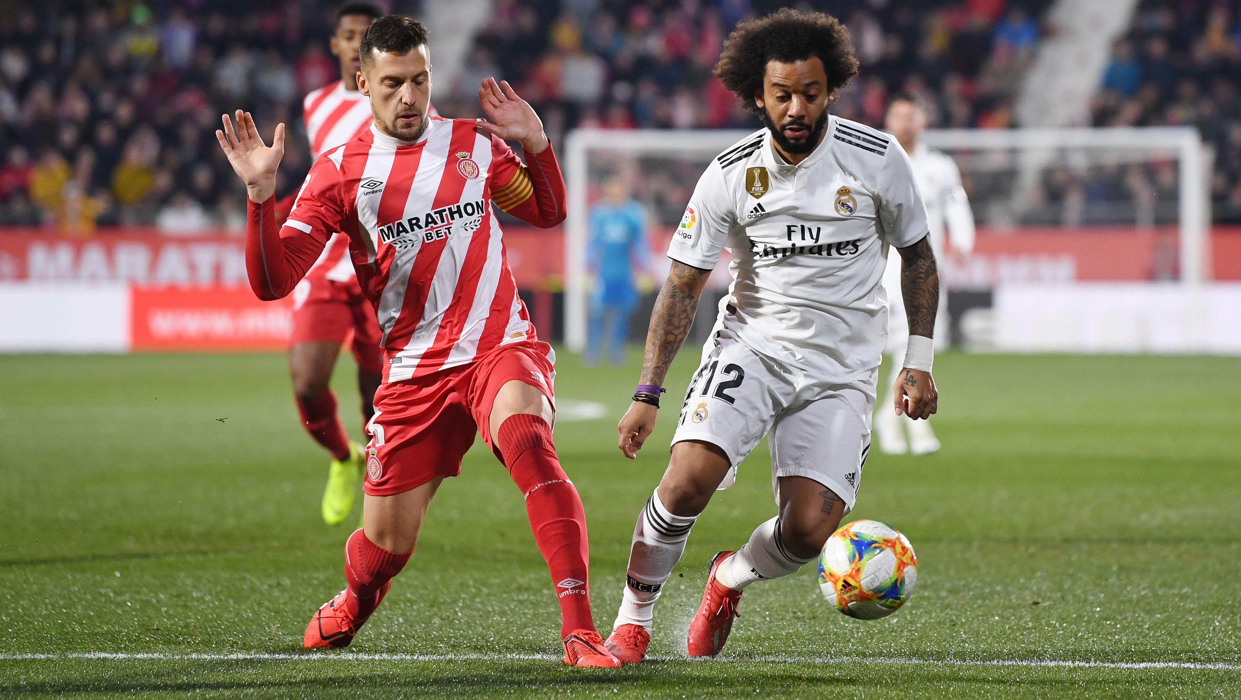 Marcelo (kanan) mengindarkan bola dari kejaran pemain Girona. Copyright: INDOSPORT