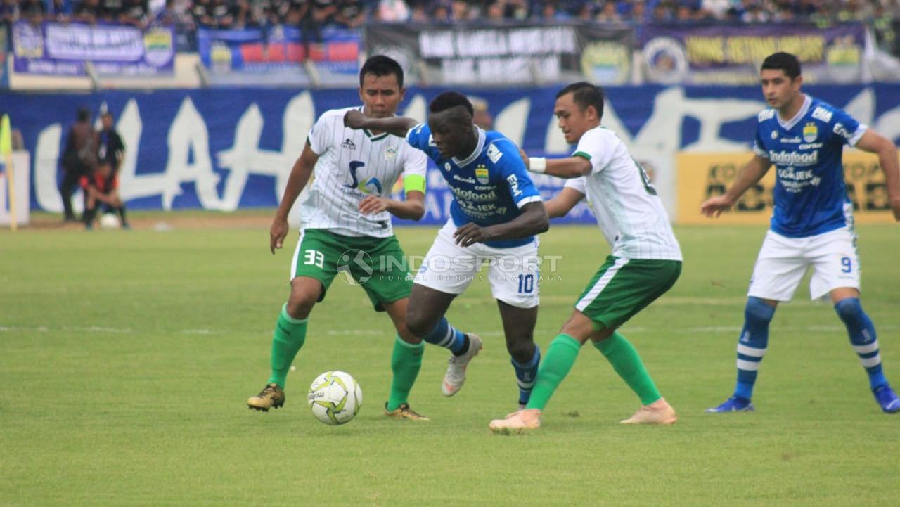 Ezechiel N'Douassel melewati dua pemain Persiwa.