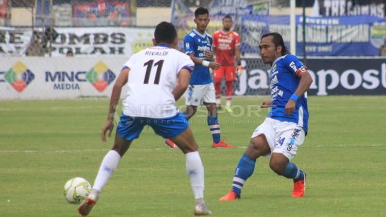 Kapten Persib, Hariono mencoba melewati pemain Arema FC, Rivaldi Copyright: Arif Rahman/INDOSPORT