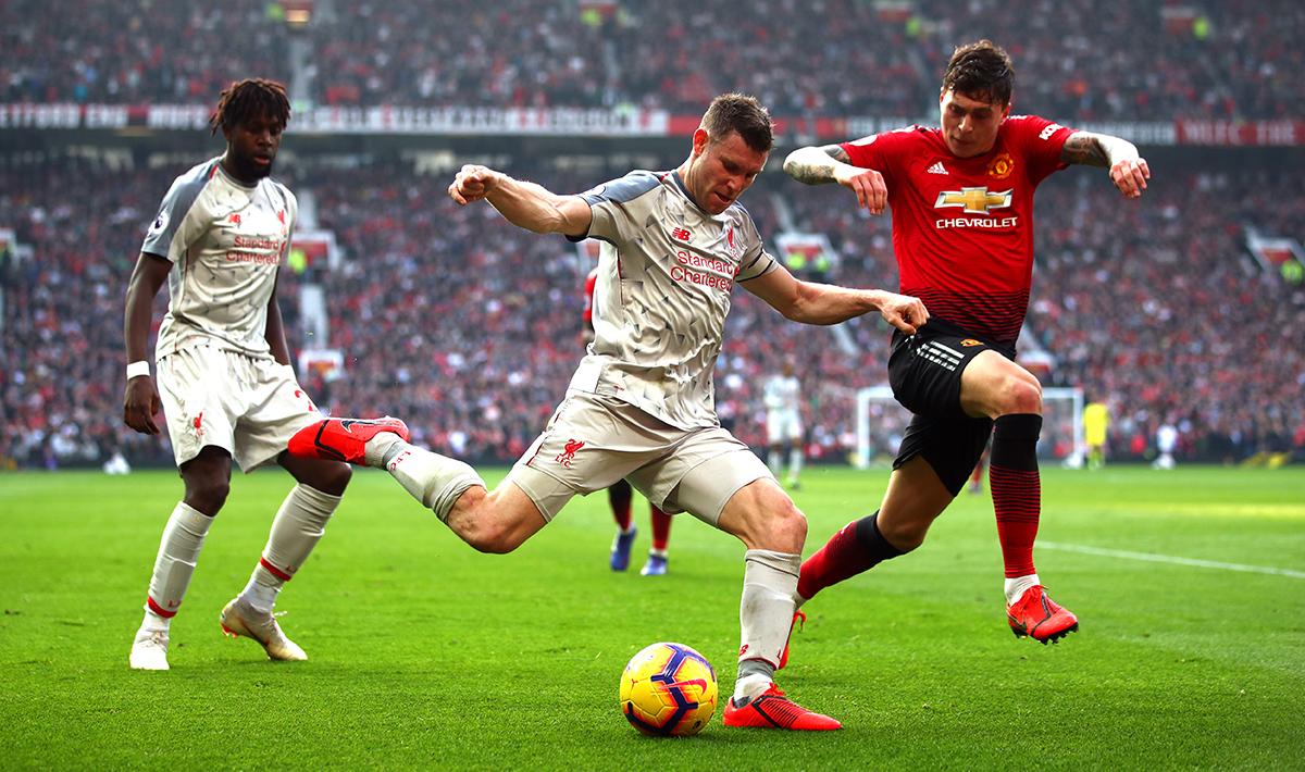 Bek sayap Liverpool, James Milner (tengah) sedang berusaha memberikan umpan ke rekannya, sementara bek Man United, Victor Lindelof berusaha menghalaunya.