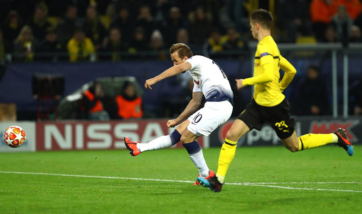 Harry Kane tengah mengeksekusi bola ke arah gawang Borussia Dortmund dan membuahkan gol pada pertandingan babak 16 besar Liga Champions 2018/19 di Stadion Westfalen, Rabu (06/03/19).
