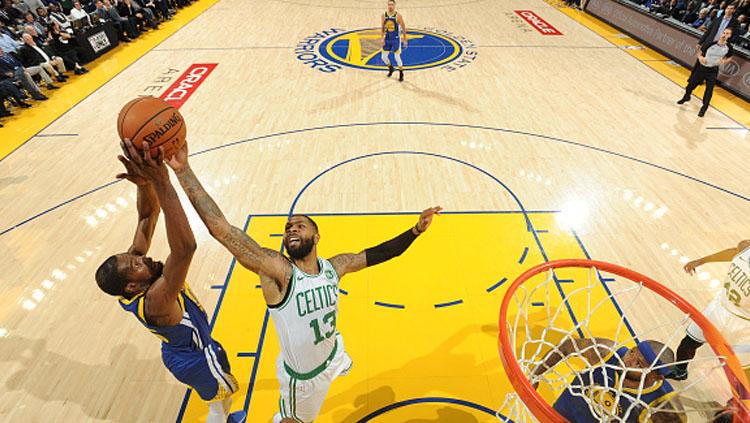 Upaya bintang Warriors, Kevin Durant (kanan) saat ingin memasukkan bola diblok oleh penggawa Celtics, Marcus Morris. Copyright: INDOSPORT