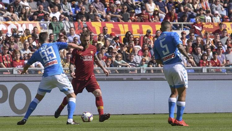 Danielle De Rossi membawa bola di antara pemain Napoli. Copyright: @OfficialASRoma