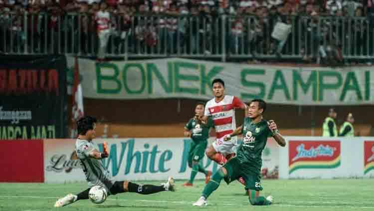 Sambil menjatuhkan diri bola cocoran bek Persebaya Hansamu Yama Pranata (kanan) tak bisa dihentikan Muhammad Ridho, kiper Madura United, meluncur deras ke gawang yang kosong. Satu gol Hansamu memastikan Persebaya menang 3-2 atas Madura Unted. Copyright: persebaya.id