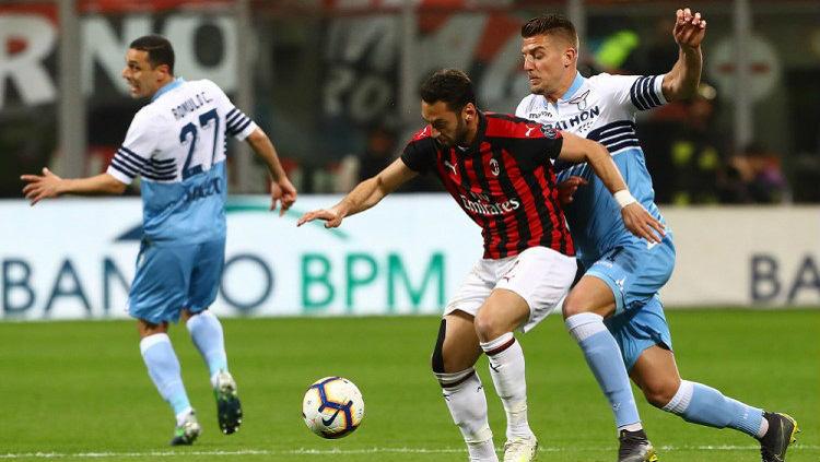 Hakan Calhanoglu berusaha mempertahankan bola dari pemain Lazio, Minggu (14/04/19), di San Siro