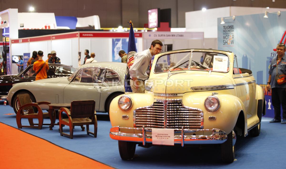 Seorang pengujung sedang mengamati mobil antik yang dipamerkan pada Indonesia Internasional Motor Shor (IIMS) 2019 hari pertama di Jiexpo Kemayoran, Jakarta, Kamis (25/04/19). Foto: Herry Ibrahim/INDOSPORT