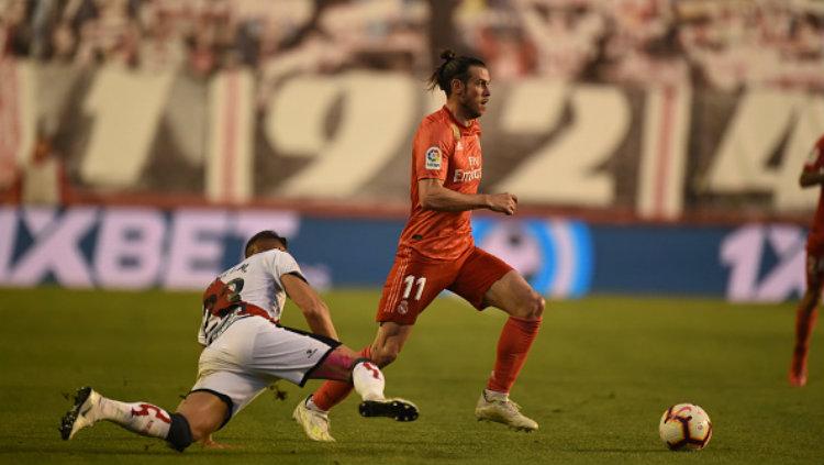 Gareth Bale menggiring bola melewati pemain Rayo Vallecano. Copyright: Denis Doyle/Getty Images