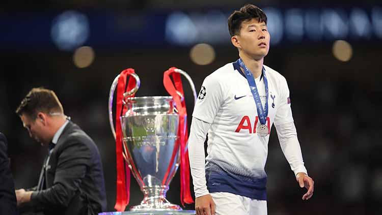Son Heung-min tampak lesu melihat trofi Liga Champions. Matthew Ashton - AMA/Getty Images