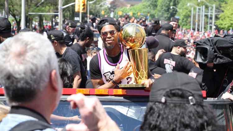Salah satu pemain Toronto Raptors tengah membawa trofi di parade juara NBA 2019.