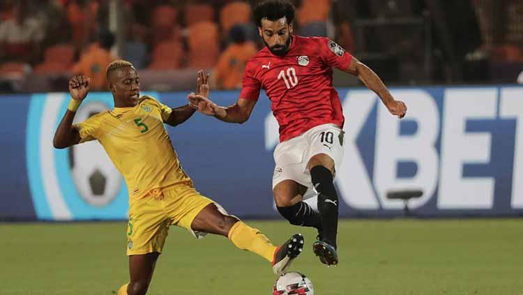 Mohamed Salah berusaha melewati jegalan dari Divine Lunga di Cairo International Stadium, Sabtu (22/06/19).