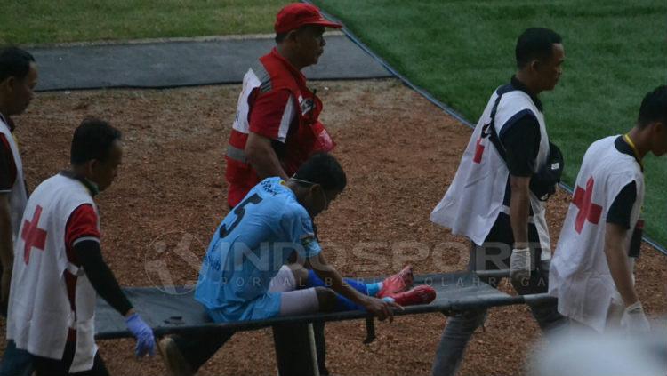 Gelandang Perserang Serang Hari Habrian, harus ditandu keluar lapangan saat melawan Sriwijaya FC di Stadion Gelora Sriwijaya Jakabaring Palembang, Minggu (23/6/19) sore. INDOSPORT/Muhammad Effendi Copyright: INDOSPORT/Muhammad Effendi