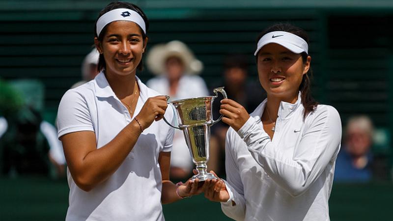 Tami Grende dan Qiu Yu Ye, memegang trofi girl's doubles di Wimbledon 2014