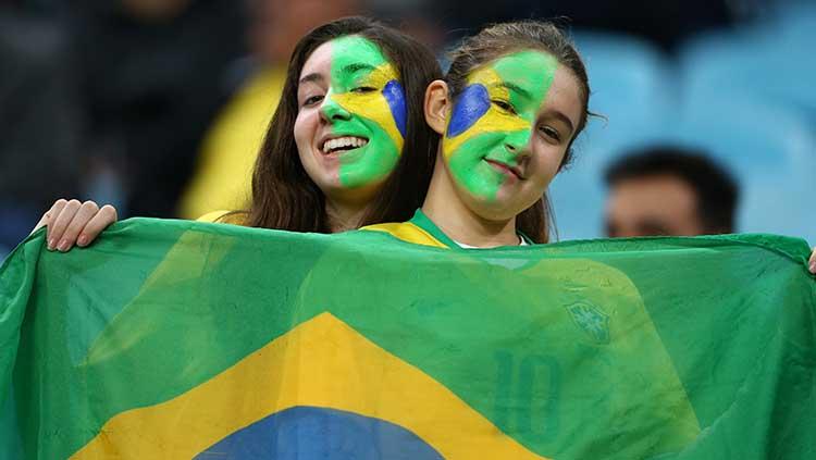 Dua suporter cantik Timnas Brasil memberikan sanyuman manisnya sambil bentangkan bendera kebangsaan mereka di Arena do Gremio, Jumat (28/06/19).