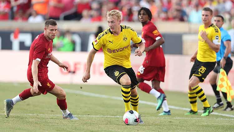 Julian Brandt tengah membawa bola dalam pengawasan James Milner. Copyright: Matthew Ashton - AMA/Getty Images)