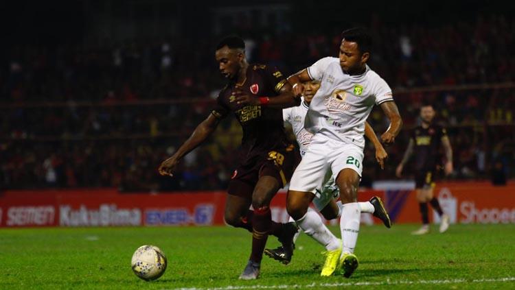 Penyerang PSM Makassar, Guy Junior (merah) berduel dengan bek Persebaya Surabaya, Otavio Dutra (putih). Copyright: Official PSM Makassar