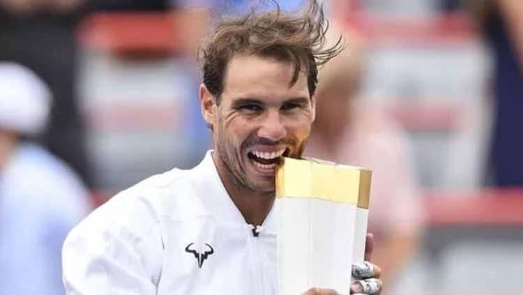 Rafael Nadal menggigit piala yang baru diraih olehnya usai kalahkan Daniil Medvedev. - INDOSPORT