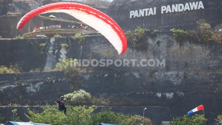 Salah satu atlet Paralayang Indonesia saat bersiap mendarat di lapangan terbuka Pantai Pandawa, Desa Kutuh, Badung, Minggu (18/08/2019). Foto : Nofik Lukman Hakim/INDOSPORT