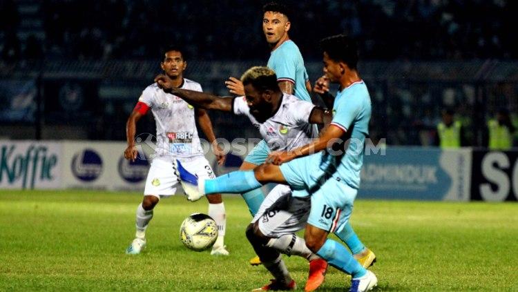 Hambali Tolib berusaha berebut bola dengan Louise Parfait pada pertandingan Liga 1 2019 antara Persela Lamongan vs TIRA Persikabo, Minggu (25/08/19) - INDOSPORT