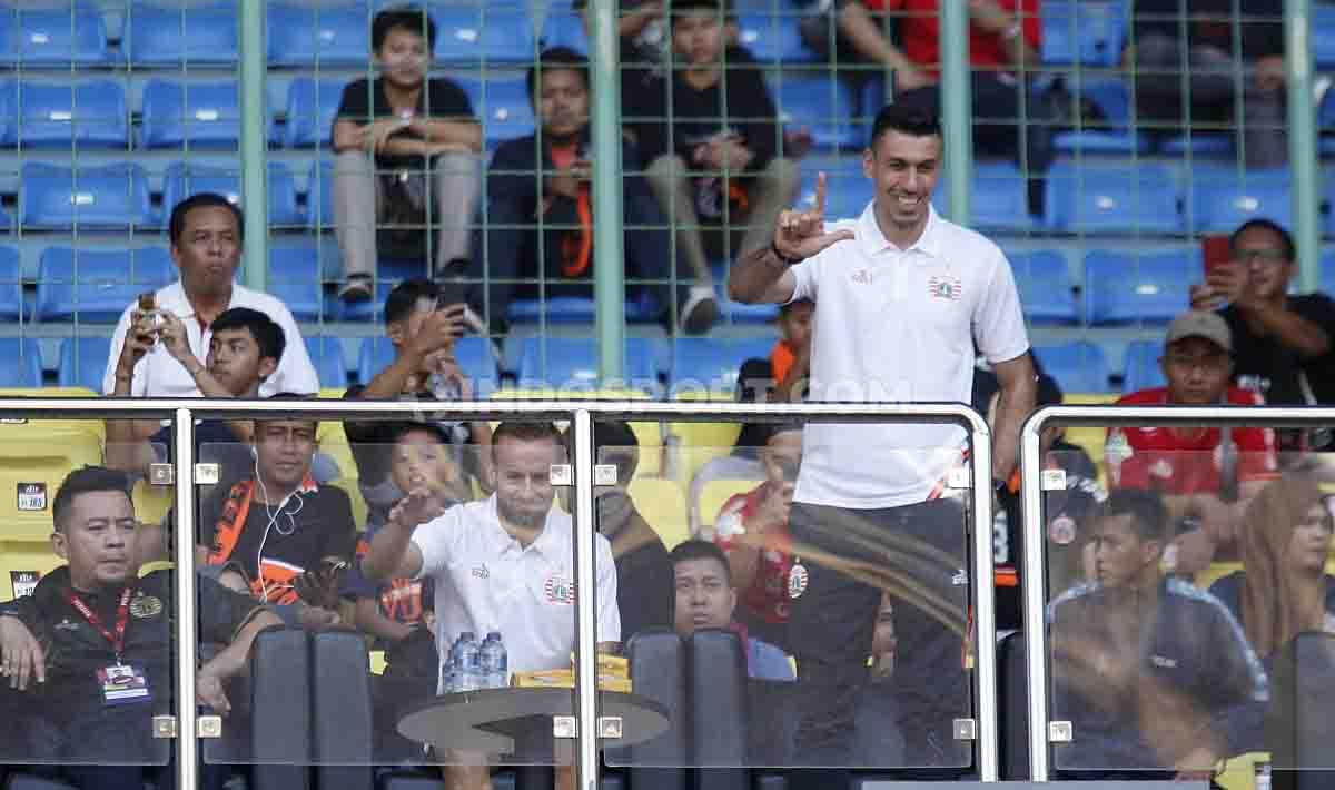 Alexandre Reame Xandao tengah berdiri memberikan simbol Jakmania di tribun dalam laga Persija Jakarta vs Perseru Badak Lampung.