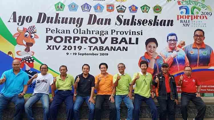 Pengurus Harian KONI Tabanan berkumpul di depan spanduk ajakan sukseskan Porprov Bali.