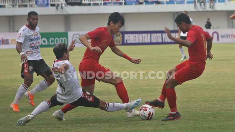 Winger Timnas U-22, Feby Eka Putra berusaha melewati tekel pemain Bali United, yang ingin merebut bola darinya.