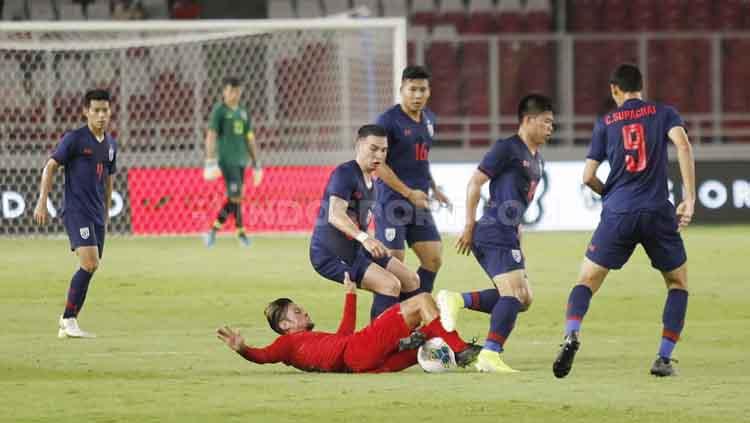 Stefano Lilipaly (bawah), terjatuh berjibaku untuk menguasai bola di tengah pengawalan para pemain Thailand, Selasa (10/09/2019). Foto: Herry Ibrahim/INDOSPORT. Copyright: Herry Ibrahim/INDOSPORT