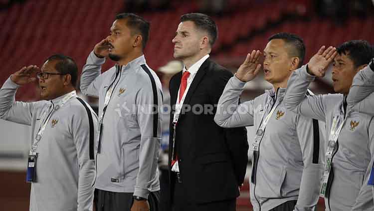 Simon McMenemy (tengah) bersama tim pelatih Timnas Indonesia di pinggir lapangan saat lagu kebangsaan Indonesia Raya dinyanyikan, Selasa (10/09/2019). Copyright: Herry Ibrahim/INDOSPORT