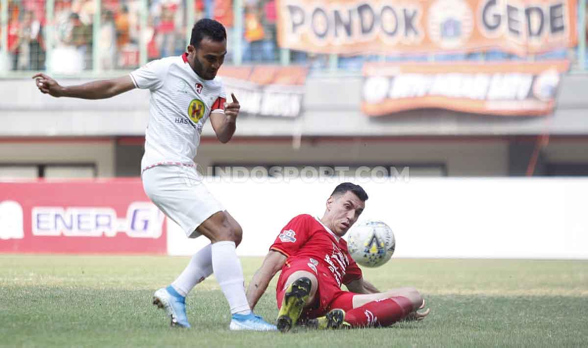 Xando berusaha mengagalkan tendangan dari Rizky Pora, kapten Barito Putera.