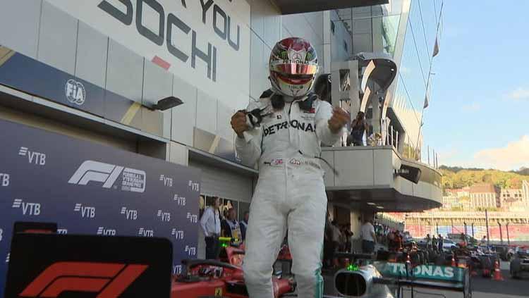 Lewis Hamilton melakukan selebrasi diatas mobilnya usai finish - INDOSPORT