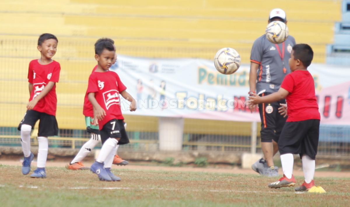 Anak-anak peserta coaching clinic yang digelar Persija unjuk gigi saat bermain sepak bola.