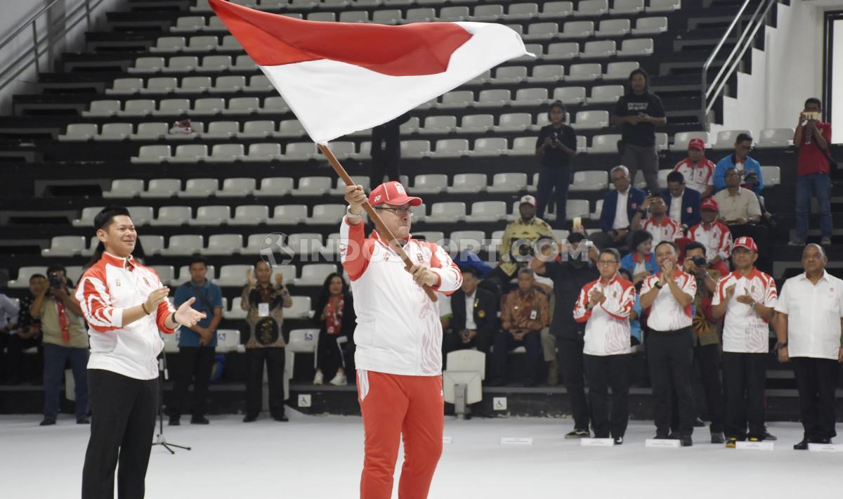 CdM (Chief de Mission) Kontingen Indonesia, Harry Warganegara menerima dan mengibarkan bendera Merah Putih pada acara pelepasan Kontingen SEA Games Indonesia 2019 di Hall A Basket GBK, Senayan, Rabu (27/11/19). - INDOSPORT