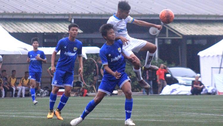 Pemain Persib U-16 berebut bola dengan pemain ‎Penang Sports School, saat laga perdana turnamen KIFC 2019 di Lapangan Progresif, Kota Bandung, Rabu (27/11/19). - INDOSPORT