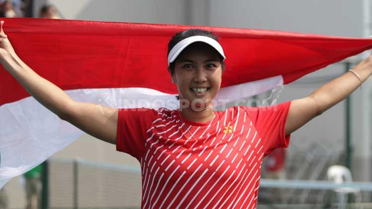 Aldila Sutjiadi mengibarkan bendera Indonesia usai meraih medali emas tenis SEA Games 2019 dari nomor tunggal putri. - INDOSPORT