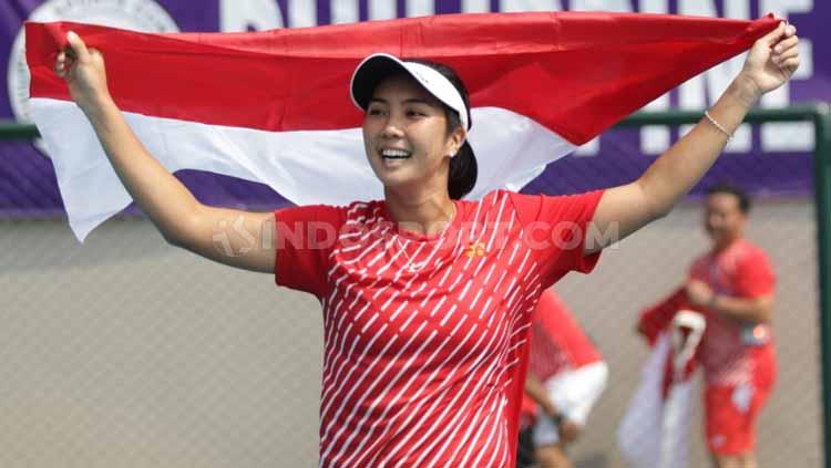 Aldila Sutjiadi mengibarkan bendera Indonesia usai meraih medali emas tenis SEA Games 2019 dari nomor tunggal putri. - INDOSPORT