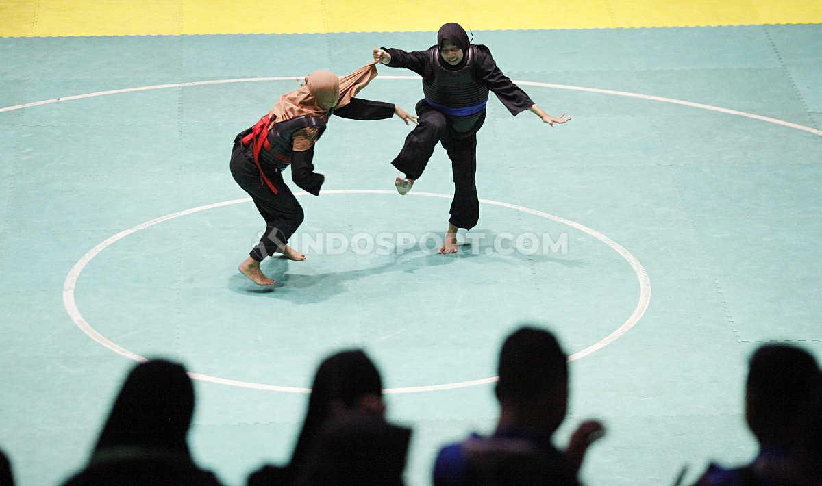 Pesilat Jawa Timur, Niken Tahta (kanan) menarik jilba lawannya pesilat Sumatera Selatan, Homsatun Nur pada laga nomer Dewasa B Putri Kejurnas dan Festival III Pagar Nusa di Padepokan Silat TMII, Jakarta, Minggu (05/01/20).