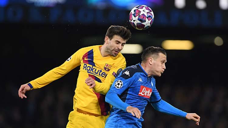 Duel udara antara bek tengah Barcelona, Gerard Pique (kiri) dengan gelandang serang Napoli, Piotr Zielinski dalam pertandingan babak 16 besar Liga Champions 2019-2020 leg pertama di San Paolo.