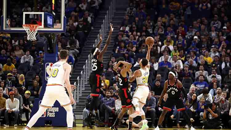 Aksi pemain megabintang Golden State Warriors, Stephen Curry saat ingin menembak bola harus dijaga oleh tiga pemain Toronto Raptors.