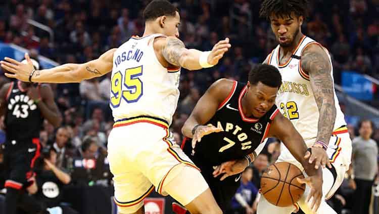 Bintang baket NBA dari tim Toronto Raptors, Kyle Lowry (tengah) dijaga ketat oleh dua pemain Golden State Warriors, Juan Toscano-Anderson (kiri) dan Marquese Chriss. Copyright: Ezra Shaw/GettyImages