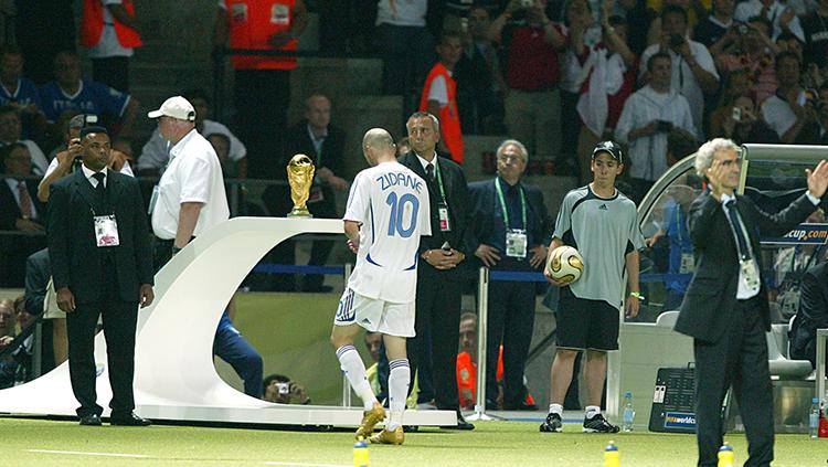 Zinedine Zidane keluar lapangan usai dikartu merah dan berhadapan dengan trofi Piala Dunia yang gagal diraihnya pada tahun 2006.