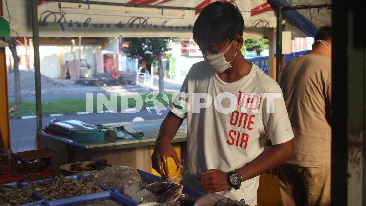 M. Rangga Aditya Saputra membantu orang tuanya berjualan ikan di pasar Taman Pondok Jati, Sidoarjo. - INDOSPORT