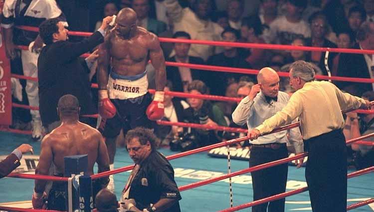 Wasit Mills Lane menunjukkan ke telinga Evander Holyfield yang berdarah setelah Tyson menggigitnya di babak ketiga.