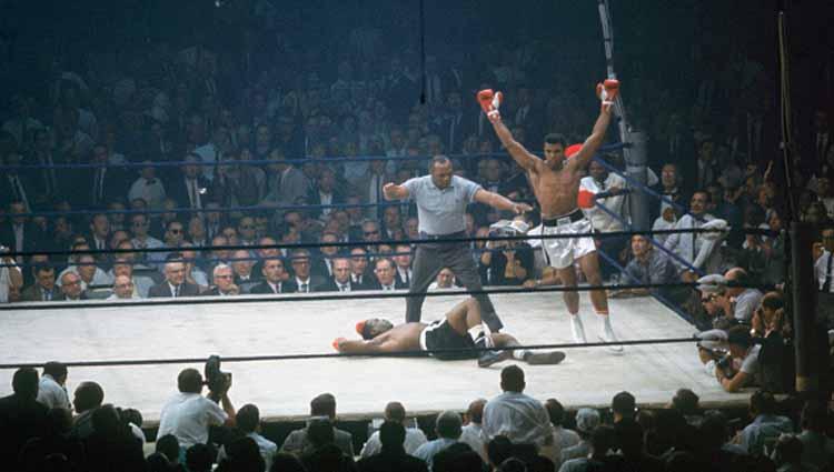 Petinju kelas berat Muhammad Ali mengangkat kedua tangan usai meng-KO Sonny Liston pada ronde pertama di Arena St. Dominic (25/05/1995). Kala itu, duel ini disinyalir adalah match fixing lantaran Sonny terlalu mudah menyerah dengan pukulan lemah.