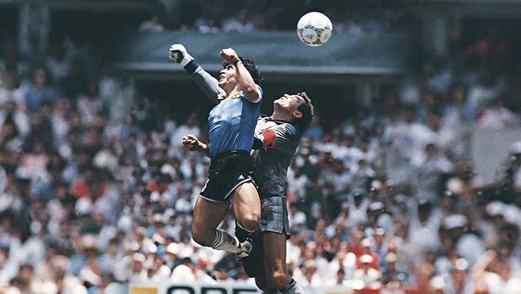 Diego Maradona (kiri) menggunakan tangannya untuk mencetak gol pertama saat melawan Inggris di perempatfinal Piala Dunia 1986. - INDOSPORT