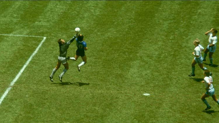 Diego Maradona (kanan) melompat dan menggunakan tangannya untuk mencetak gol pertama saat melawan Inggris di perempatfinal Piala Dunia 1986. Gol tersebut kini dikenal dengan sebutan 'Gol Tangan Tuhan'.